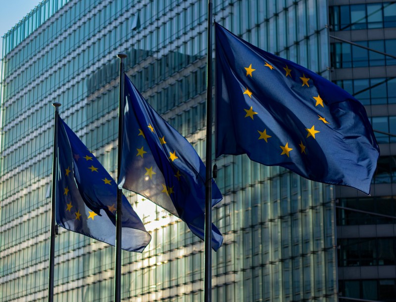 Tres banderas de la Unión Europea ondeando frente a un edificio institucional