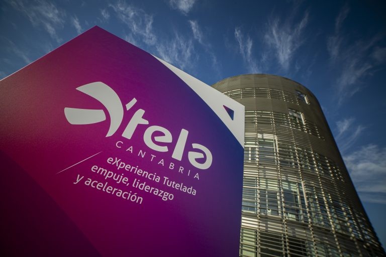 cartel Xtela en tonos rosados-morados oscuros con edificio de fondo