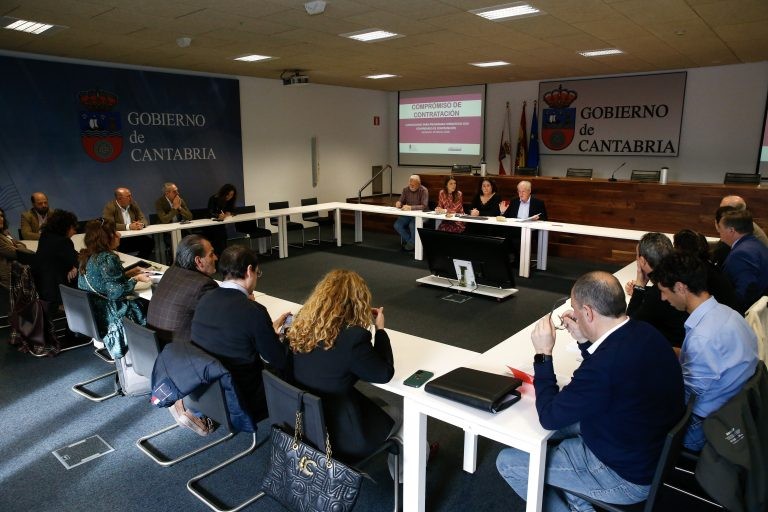 varias personas reunidas sentadas a mesas formando un cuadrado