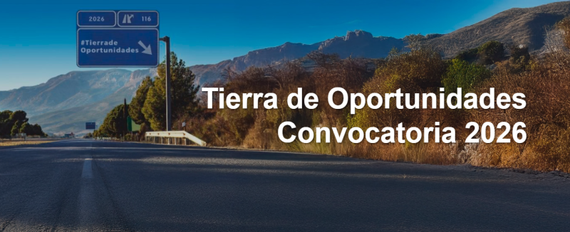 Una carretera entre árboles con cartel de salida que pone #TierradeOportunidades