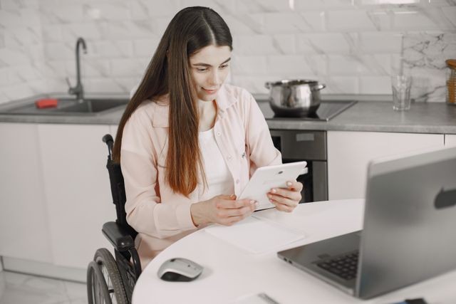 chica en silla de ruedas frente a mesa con portátil
